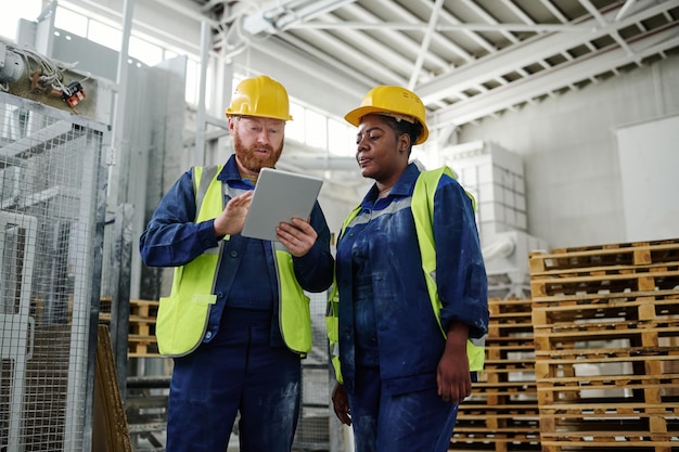 Jonge mannelijke ingenieur met tablet die presentatie maakt aan vrouwelijke collega