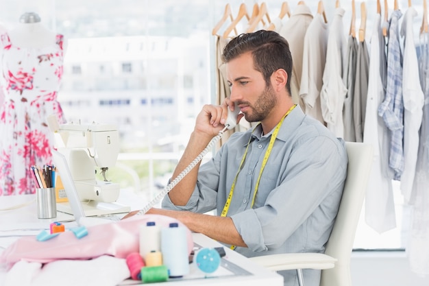 Jonge mannelijke manierontwerper die telefoon met behulp van