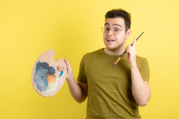 jonge mannelijke schilder met palet en penseel schilderen.