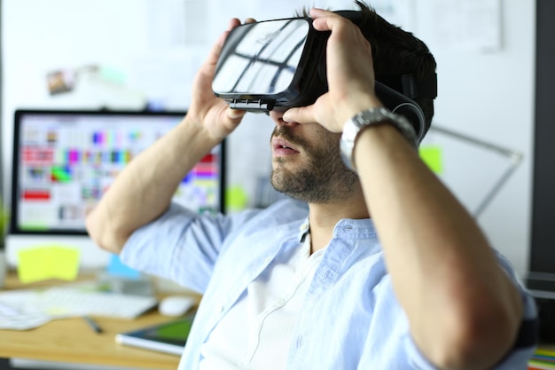Foto jonge mannelijke softwareprogrammeur die een nieuwe app test met 3d virtual reality-bril op kantoor