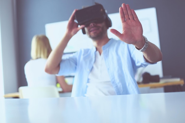 Jonge mannelijke softwareprogrammeur die een nieuwe app test met 3D virtual reality-bril op kantoor