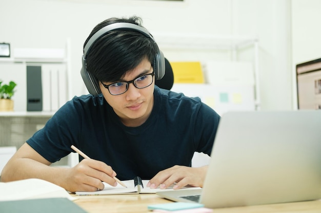 Jonge mannelijke student studeert thuis Hij gebruikt laptop en leert onlinexD