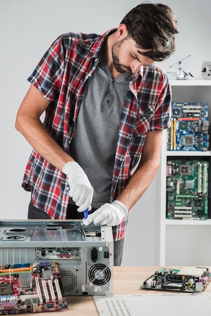 Jonge mannelijke technicus die aan computer CPU in workshop werkt