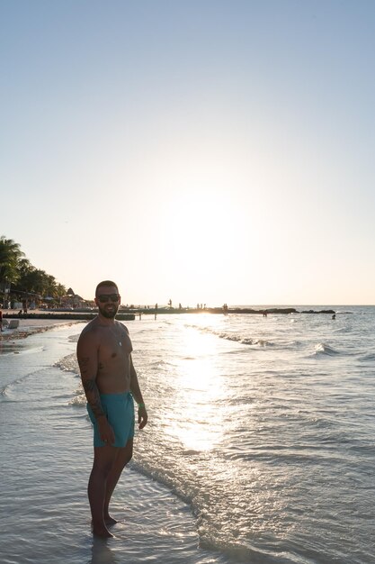 Jonge mannelijke toerist op Holbox-strand bij zonsondergang