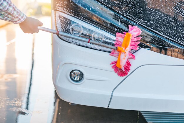 Jonge mannelijke werknemer wassen bus.