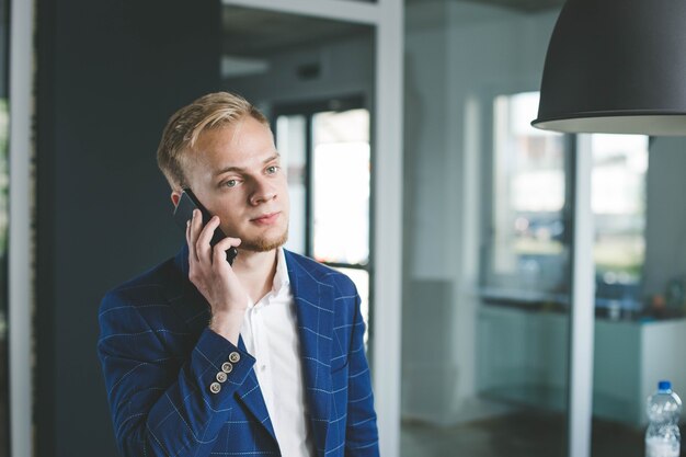 jonge mannelijke zakenman spreekt aan de telefoon over een zakelijk project