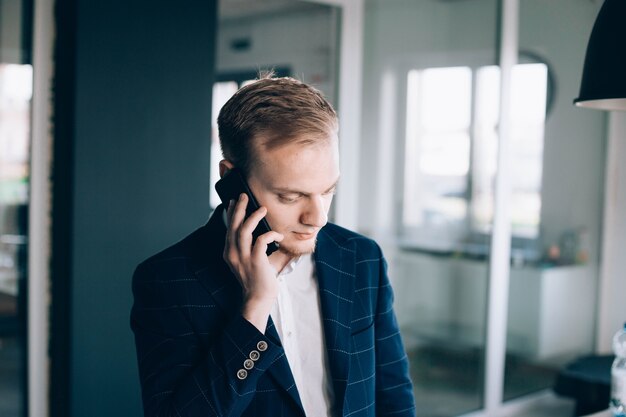 jonge mannelijke zakenman spreekt aan de telefoon over een zakelijk project