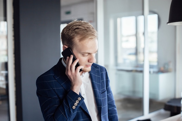 jonge mannelijke zakenman spreekt aan de telefoon over een zakelijk project