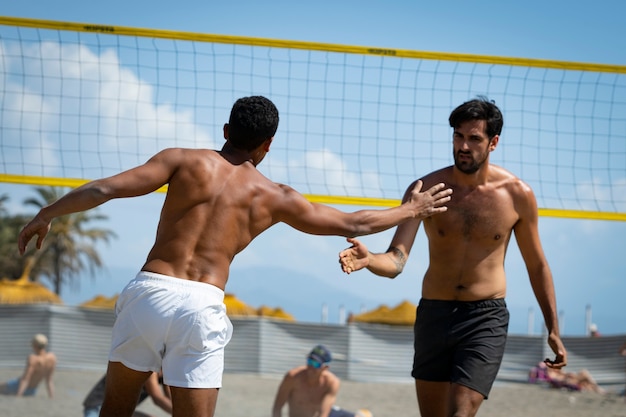 Foto jonge mannen die op een zonnige dag beachvolleybal spelen op het strand