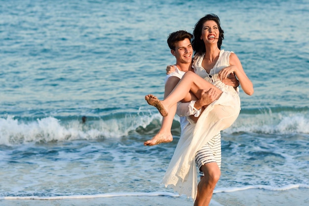 Jonge mannen dragen vrouwen op het strand.