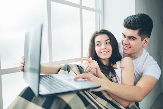 Jonge mannen en vrouwen werken aan de computer of zoeken informatie op het internet bij een raam vol zonlicht