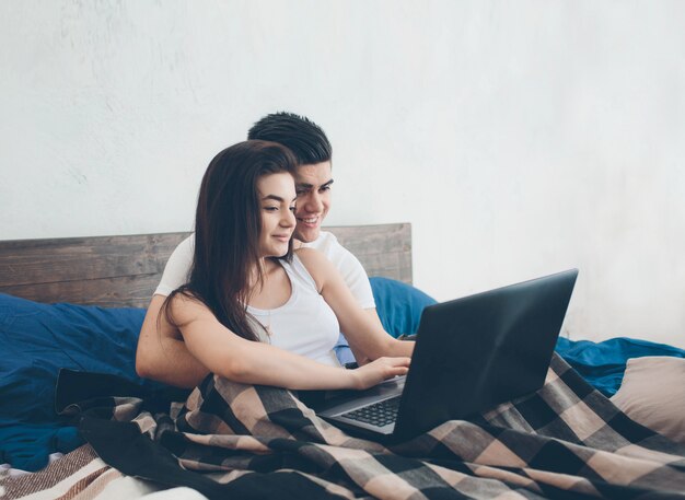 Jonge mannen en vrouwen werken aan de computer of zoeken informatie op internet op het bed.