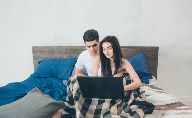 Jonge mannen en vrouwen werken op de computer of zoeken informatie op internet op het bed