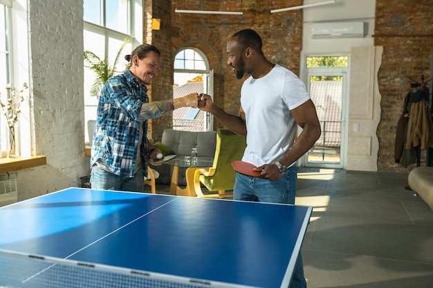 Jonge mannen tafeltennissen op de werkplek, plezier maken