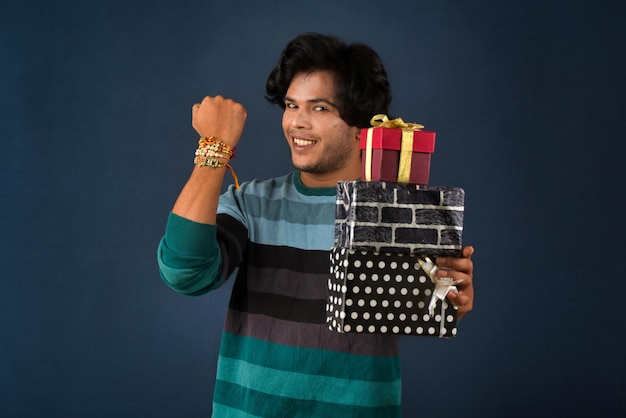 Jonge mannen tonen Rakhi op zijn hand met geschenkdoos ter gelegenheid van Raksha Bandhan-festival