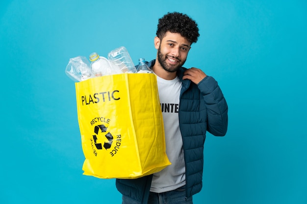 Jonge Marokkaanse man die een zak vol plastic flessen houdt om geïsoleerd te recyclen