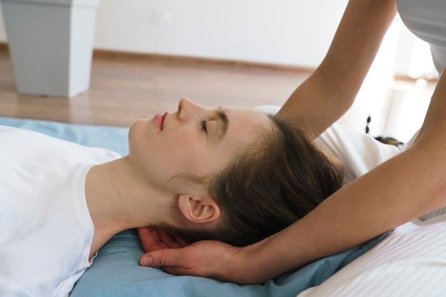 Jonge masseuse doet een Thaise massage op de vloer en masseert haar nek en schouders.