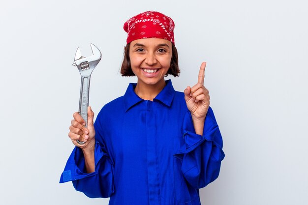 Jonge mechanische vrouw die een geïsoleerde sleutel houdt die nummer één met vinger toont.