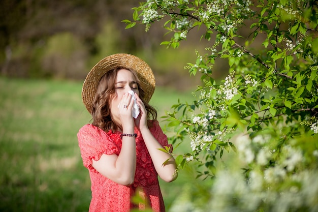 Jonge meisjes blazende neus en het niezen in weefsel voor bloeiende boom. Seizoensgebonden allergenen die mensen treffen. Mooie dame heeft rhinitis.