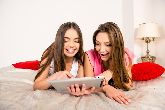 Jonge meisjes die op bed met tablet liggen