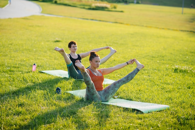 Jonge meisjes doen yoga buiten in het park tijdens zonsondergang. gezonde levensstijl.