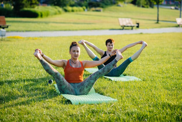 Jonge meisjes doen yoga buiten in het park tijdens zonsondergang. Gezonde levensstijl.