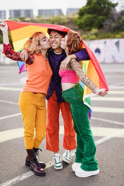 Foto jonge meisjes kussen aziatische vriend tijdens gay pride-parade terwijl ze lgbt-regenboogvlag vasthouden