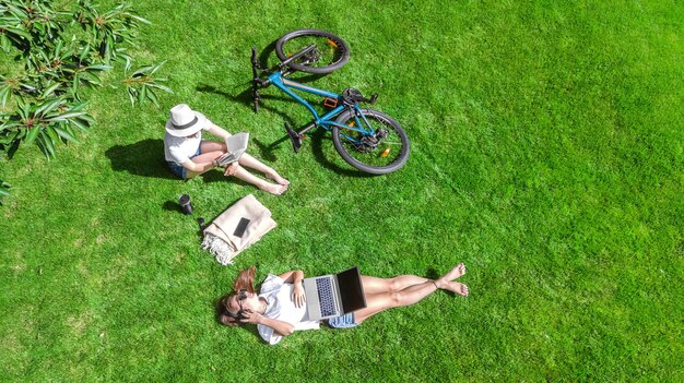 Foto jonge meisjes met fietsen in het park met een laptop en koptelefoon twee studenten meisjes die studeren