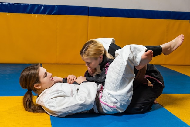 Jonge meisjes oefenen Braziliaans jiu jitsu in de sportschool