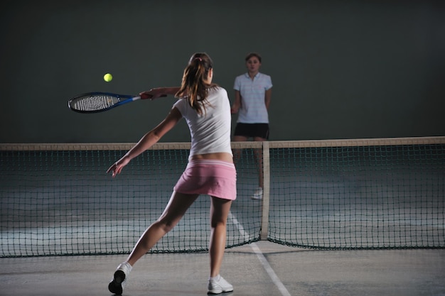 Jonge meisjes spelen tennis binnen.