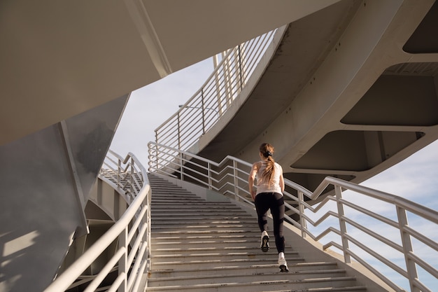 Jonge meisjesatleet die op de treden van de brug loopt