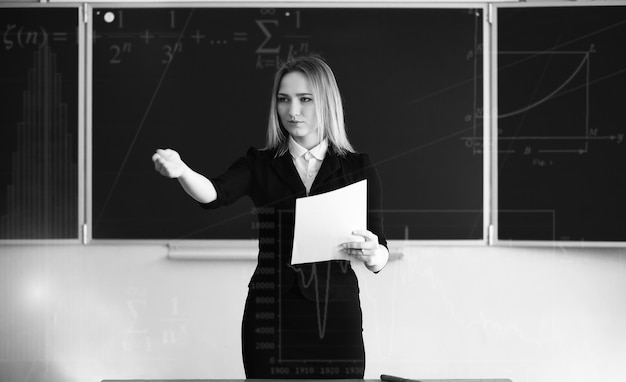 Jonge meisjesleraar op de basisschool in de klas voor bord