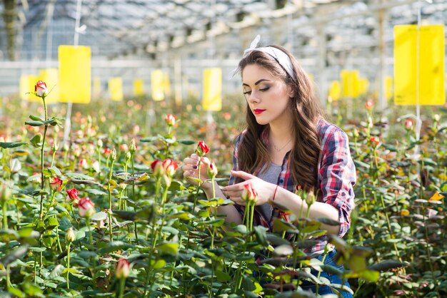 Jonge meisjestuinman of kasarbeider zorgt voor bloemen in de kas