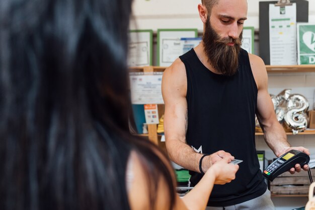 Jonge mens binnen gebruikend creditcardlezer