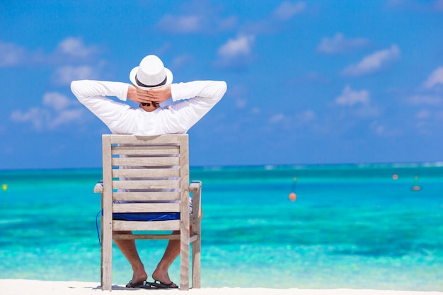 Jonge mens die de zomer van vakantie op tropisch strand geniet