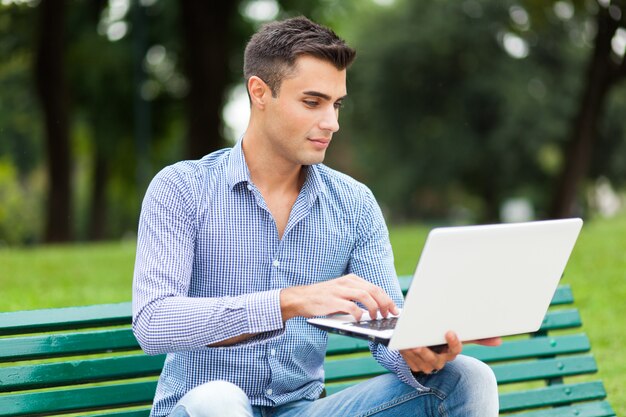 Jonge mens die een laptop computer in openlucht met behulp van