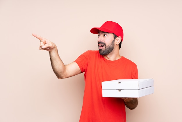 Jonge mens die een pizza houdt die weg richt