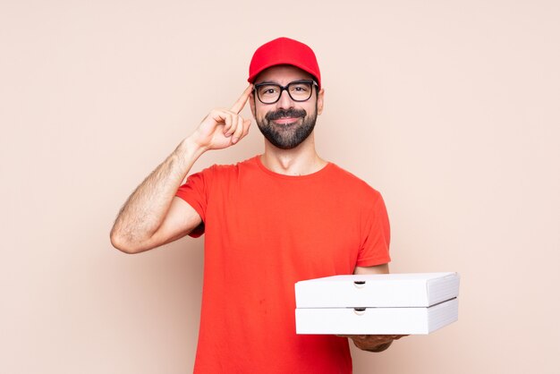 Jonge mens die een pizza over geïsoleerde achtergrond met glazen houdt en gelukkig