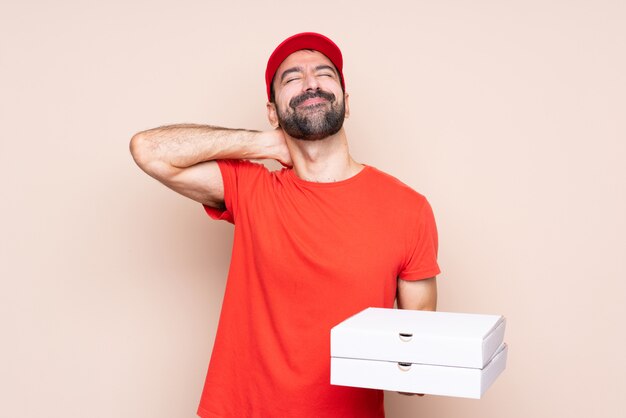 Jonge mens die een pizza over geïsoleerde muur met halspijn houdt