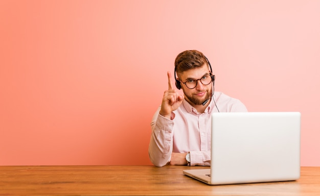 Jonge mens die in een call centre werkt dat nummer één met vinger toont.