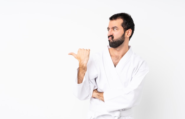 Jonge mens die karate over geïsoleerde witte ongelukkig doet en aan de kant richt