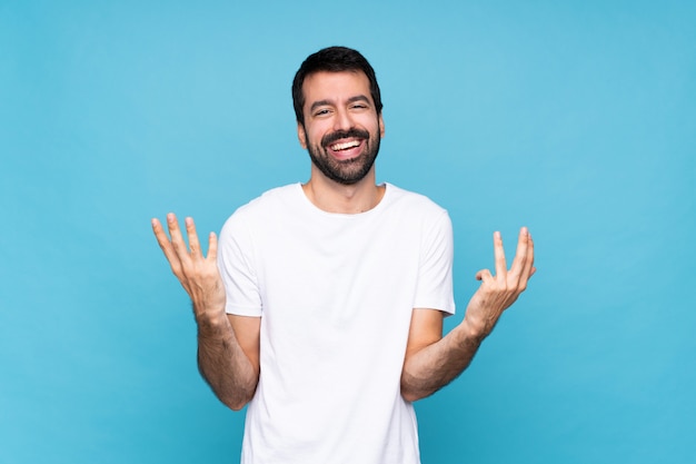 Jonge mens die met baard over geïsoleerd blauw veel glimlacht