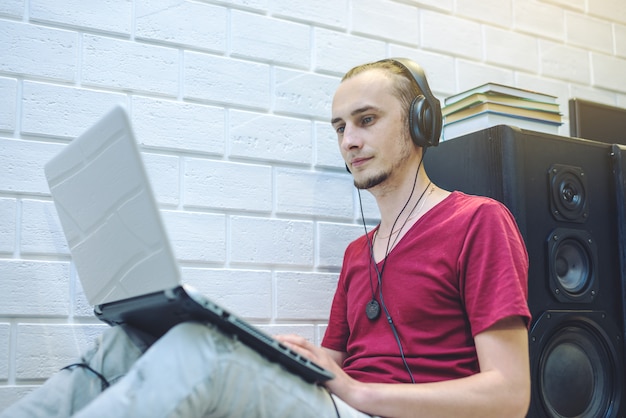 Jonge mens die met hoofdtelefoons aan lessen luistert en bij laptop werkt. Het concept van technologie en modern onderwijs