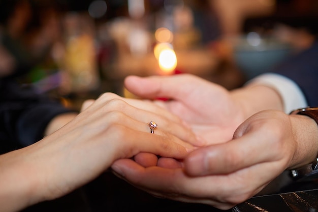 Jonge mens die ring op vinger van zijn verloofde zet na close-up van het huwelijksaanzoek