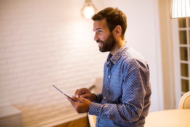 Jonge mens die van huis aan digitale tablet werkt