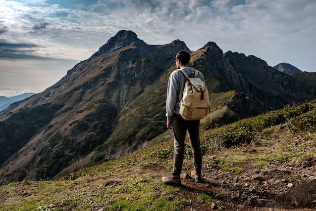 Jonge mens die zich bovenop klippenbergen bevindt