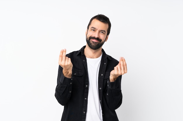 Jonge mens met baard over geïsoleerd wit die geldgebaar maken