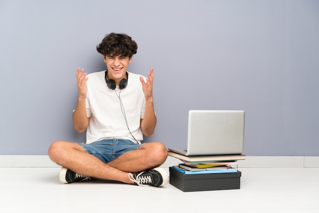 Foto jonge mens met zijn laptop zitting één vloer het lachen