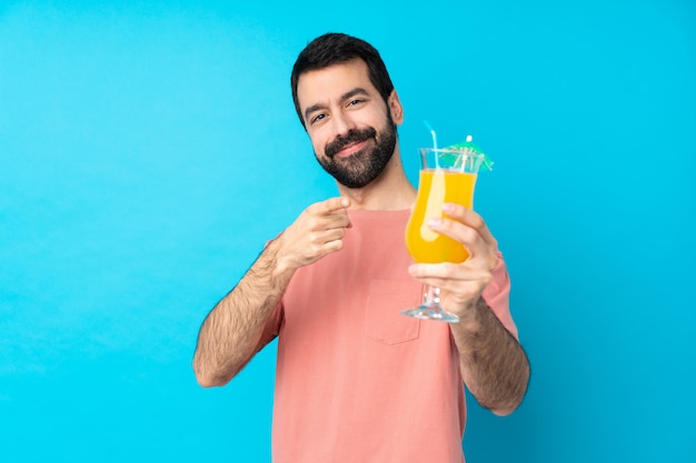 Jonge mens over het houden van een cocktail over geïsoleerde blauwe muur