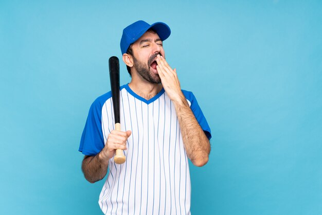 Jonge mensen speelhonkbal over geïsoleerde blauwe muur die en wijd open mond geeuwen behandelen met hand